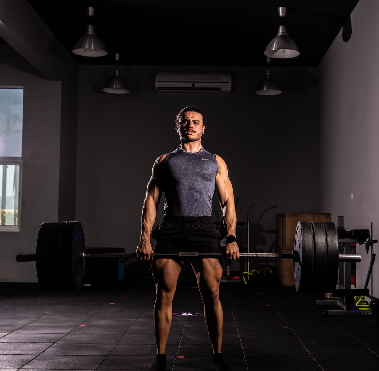 team-01 A strong adult man lifting a large barbell indoors, showcasing strength and fitness.