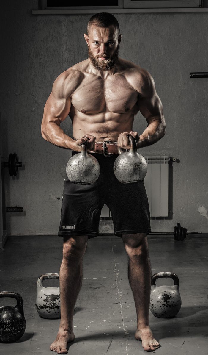 The Art of Drawing Readers In: Your attractive post title goes here Shirtless man with muscular build lifting kettlebells indoors, showcasing strength and fitness.