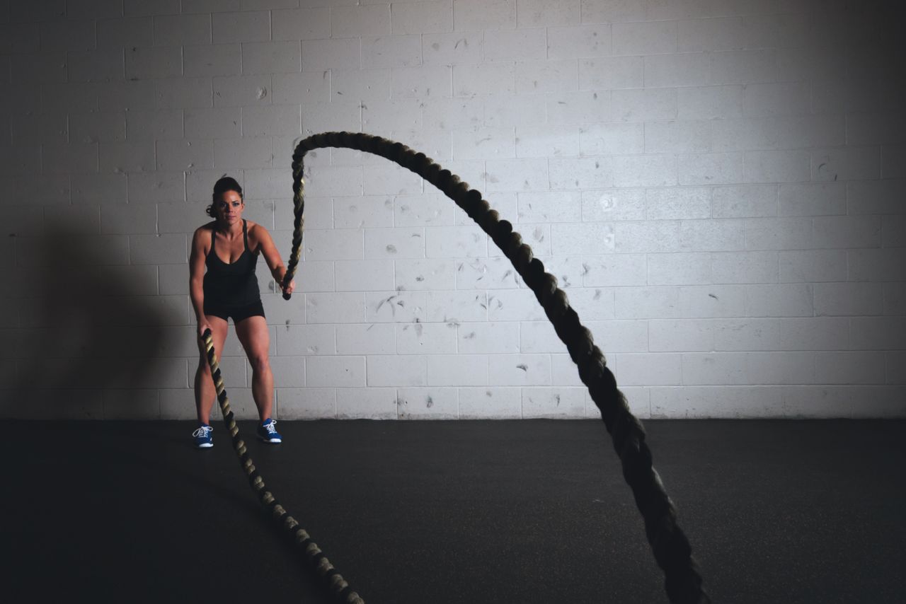 Crafting Captivating Headlines: Your awesome post title goes here A focused woman performs a dynamic battle rope exercise in a gym setting, demonstrating strength and fitness.
